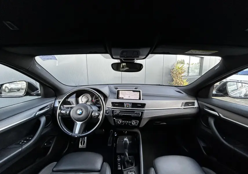 Intérieur noir de BMW X2 F39 2021, vue avant sur tableau de bord avec écran GPS et volant M cuir.