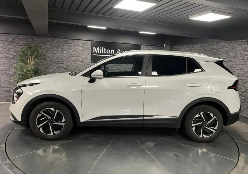 KIA SPORTAGE blanc nacré vu de profil côté gauche, avec jantes alliage noires et vitres surteintées.