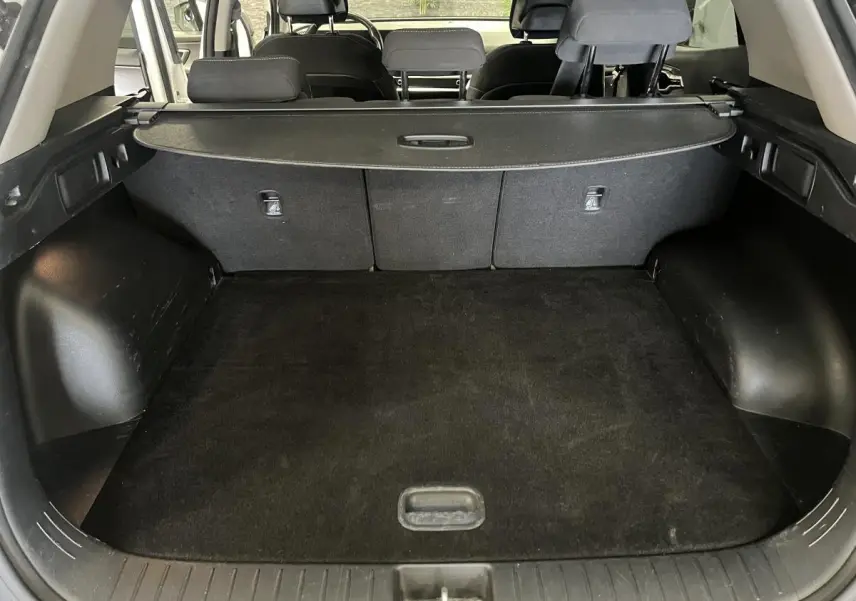 Coffre ouvert du Kia Sportage blanc 2022, montrant l'espace de chargement et la plage arrière noire.