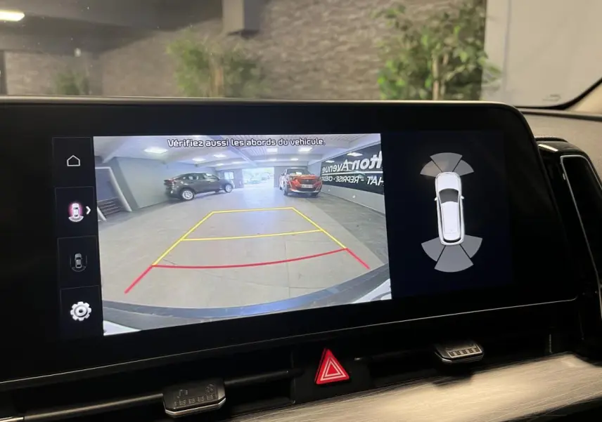 Affichage de la caméra de recul du Kia Sportage blanc, avec lignes de guidage et capteurs de proximité visibles.