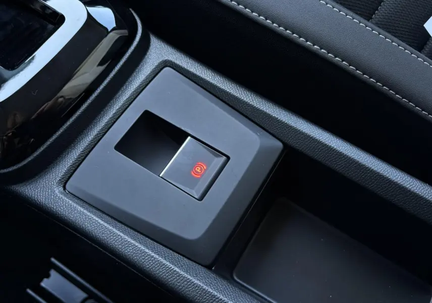 Bouton de frein de stationnement électrique allumé sur la console centrale noire du Citroën C3 Aircross 2025.