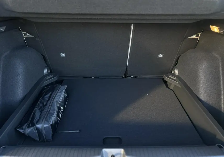 Coffre spacieux noir du Citroën C3 Aircross 2025 avec sac de secours visible sur le côté gauche.