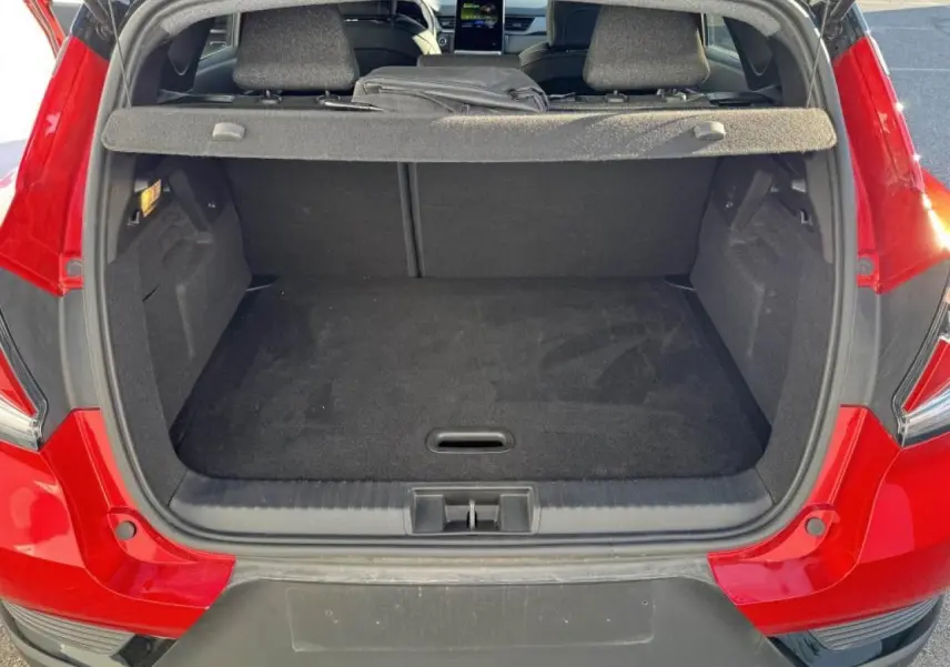 Coffre ouvert vu de l'arrière d'un Renault Captur rouge flamme avec toit noir, montrant l'espace de chargement vide.