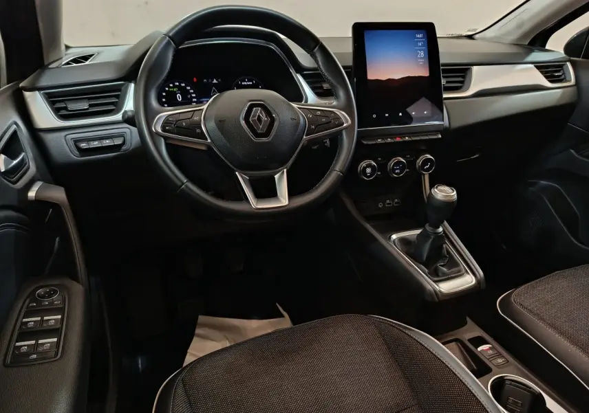 Intérieur Renault Captur Techno TCe 90 2024, vue avant centrée sur volant, écran tactile vertical et boîte manuelle noire.