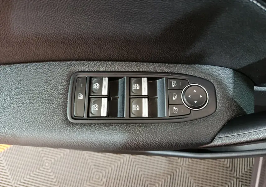 Gros plan sur les commandes de lève-vitres et rétroviseurs côté conducteur du Renault Captur gris foncé 2024.