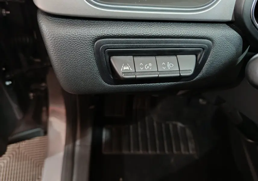 Boutons de réglage de l'aide à la conduite et des phares sur le tableau de bord côté conducteur d'un Renault Captur gris foncé.