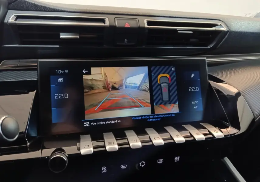 Vue rapprochée de l’écran tactile central du tableau de bord de la Peugeot 508 gris clair, affichant la caméra de recul et les commandes climatisation.