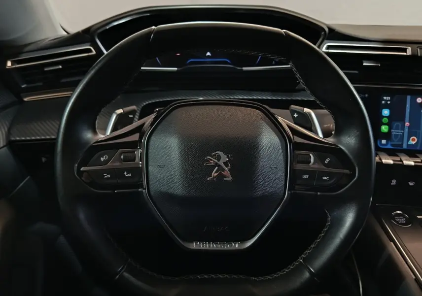 Vue rapprochée du volant cuir noir de la Peugeot 508 2020 avec commandes intégrées et tableau de bord numérique.