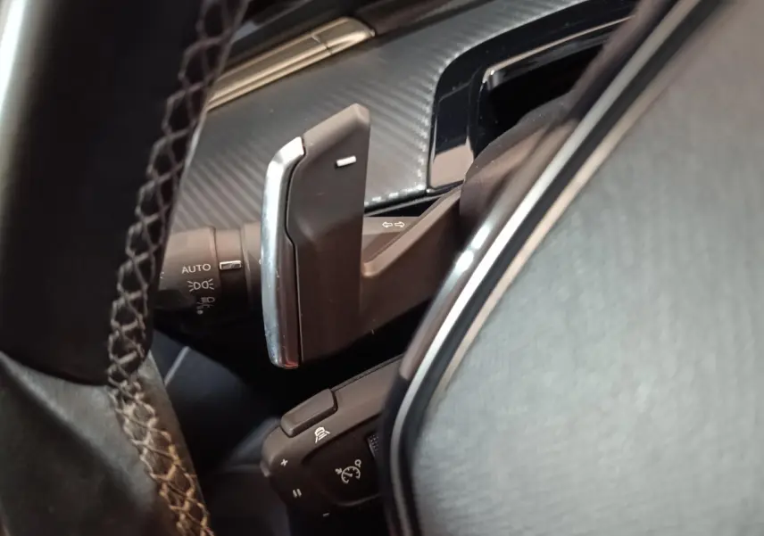 Gros plan sur la commande au volant et levier de clignotant dans l’habitacle noir du Peugeot 508 gris clair.