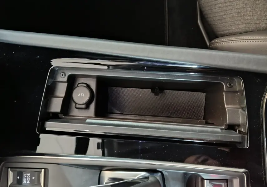 Gros plan sur la console centrale noire brillante de la Peugeot 508 gris clair, avec prise 12V et bouton Drive Mode visible.
