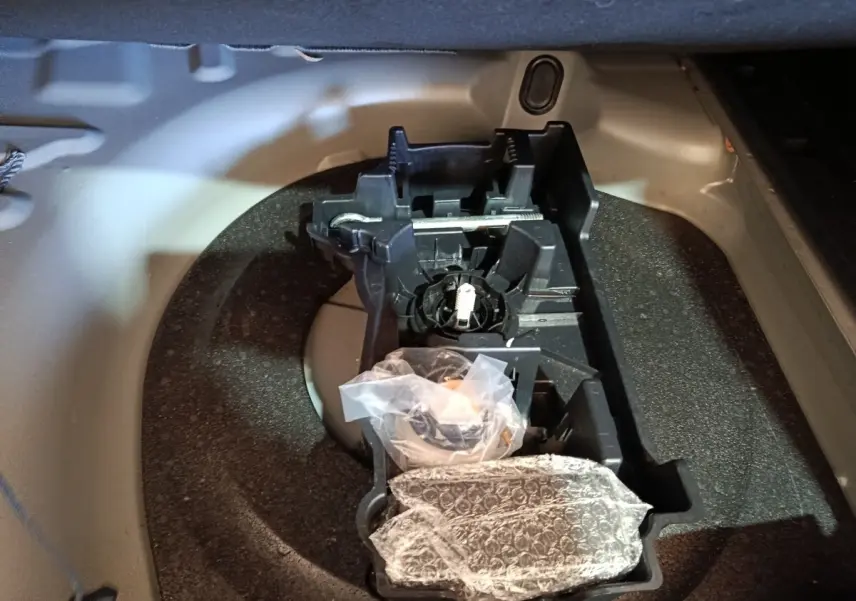 Vue rapprochée de la roue de secours et du rangement à outils dans le coffre gris clair d’une Peugeot 508 2020.