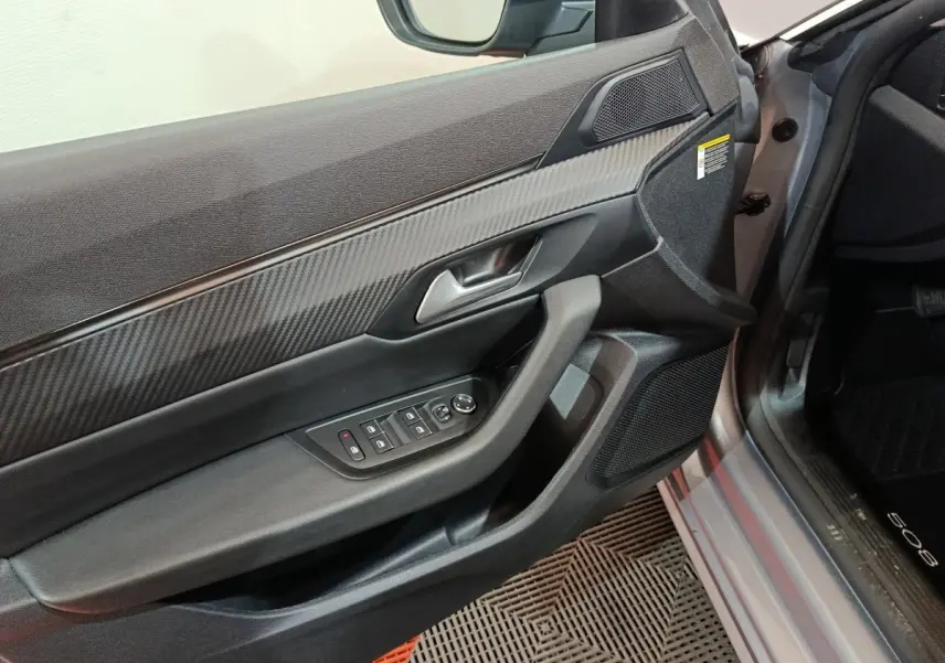 Vue intérieure du panneau de porte côté conducteur gris clair de la Peugeot 508 avec commandes électriques et finition carbone.