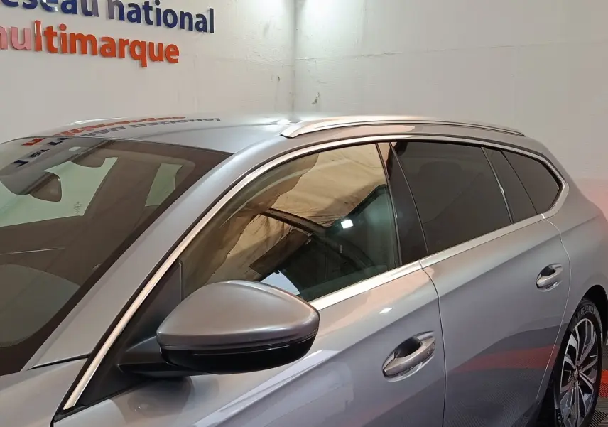 Vue côté gauche d'un Peugeot 508 gris clair, mettant en valeur la ligne de toit et le rétroviseur extérieur.