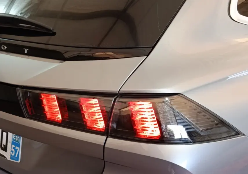 Feu arrière droit allumé sur Peugeot 508 gris clair vue en gros plan, soulignant la ligne de coffre et la lunette arrière.