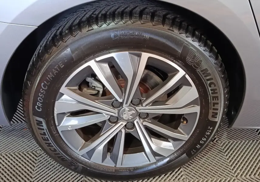 Gros plan sur la roue avant droite gris clair d'une Peugeot 508 avec jante alliage et pneu Michelin CrossClimate 2.