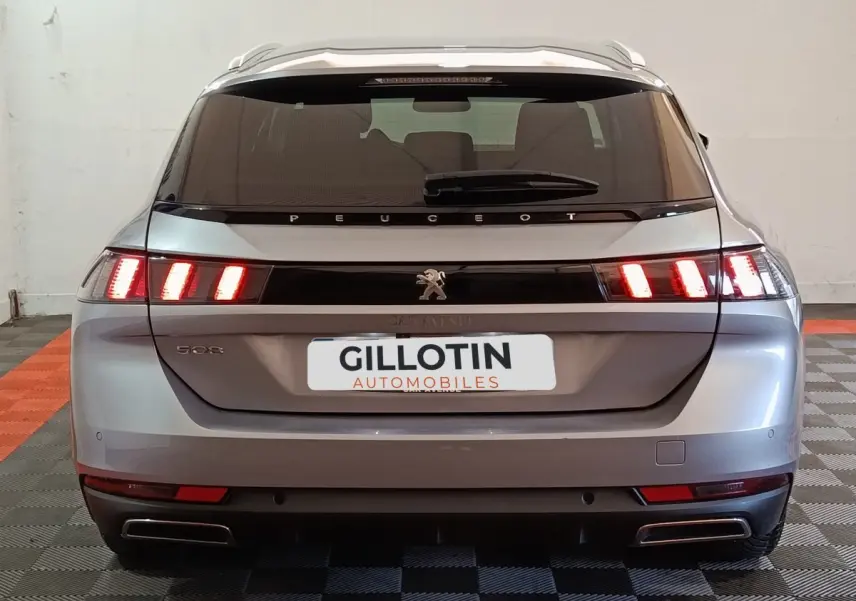Vue arrière d'une Peugeot 508 gris clair avec feux LED allumés et double sortie d'échappement rectangulaire.