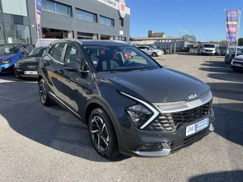 KIA Sportage gris Eclipse métal vu en 3/4 avant droit, avec calandre distinctive et jantes bi-ton.