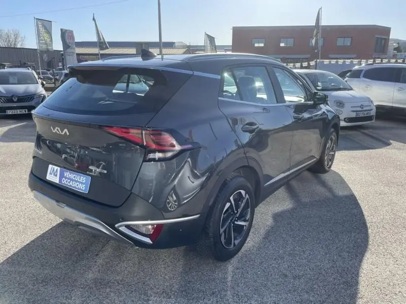 Vue 3/4 arrière droite d’un KIA Sportage gris Eclipse Métal 2023 avec feux LED et jantes alliage bicolores.