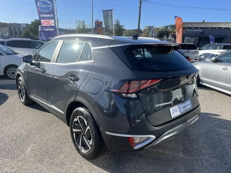 Vue 3/4 arrière droite d'un Kia Sportage gris Eclipse Metal 2023 avec feux arrière LED et jantes alliage bicolores.