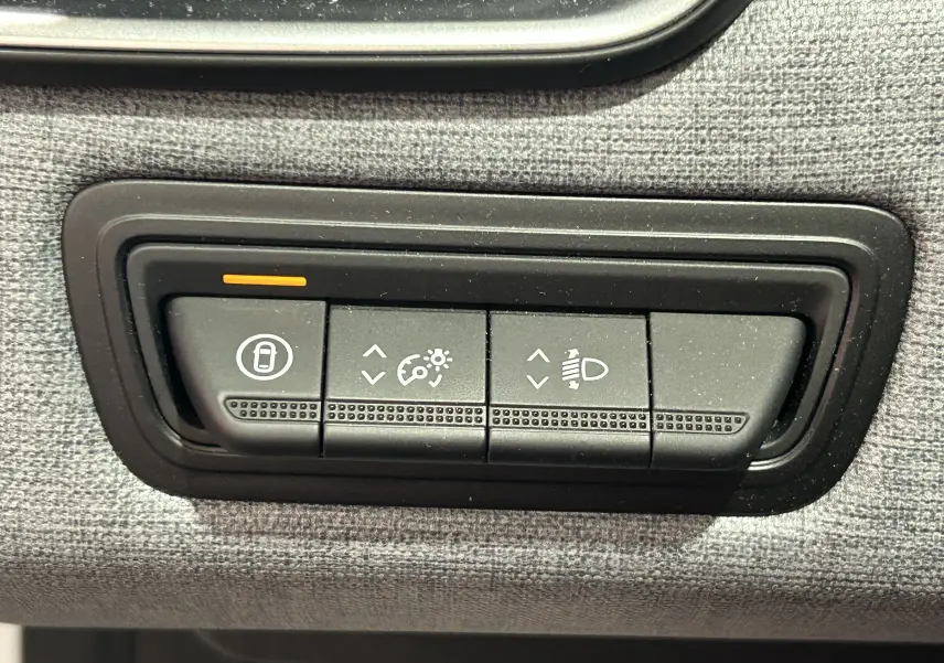 Gros plan sur les commandes de réglage d’éclairage et verrouillage intérieur de la Renault Clio V blanche, tableau de bord côté conducteur.