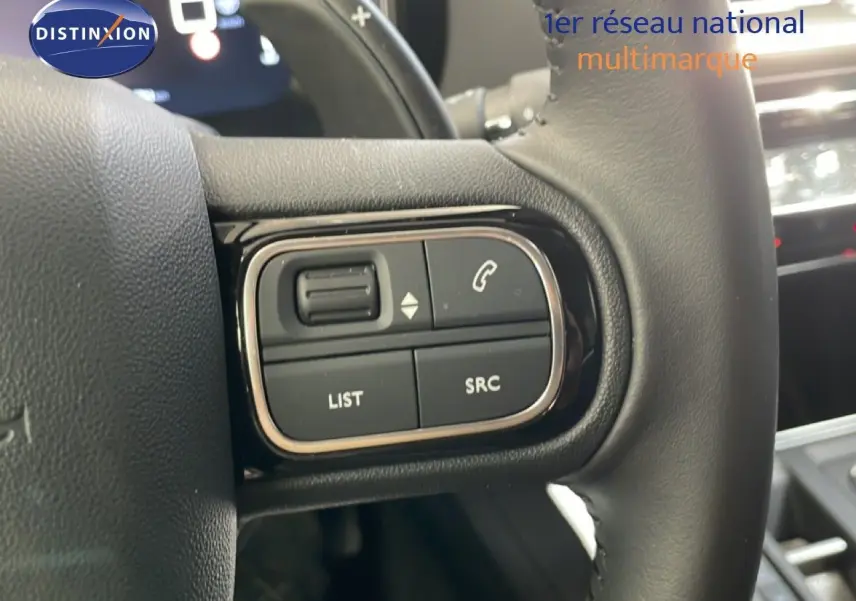 Gros plan sur les commandes gauche du volant noir du Citroën C5 Aircross gris platinium 2025, avec boutons multifonctions.