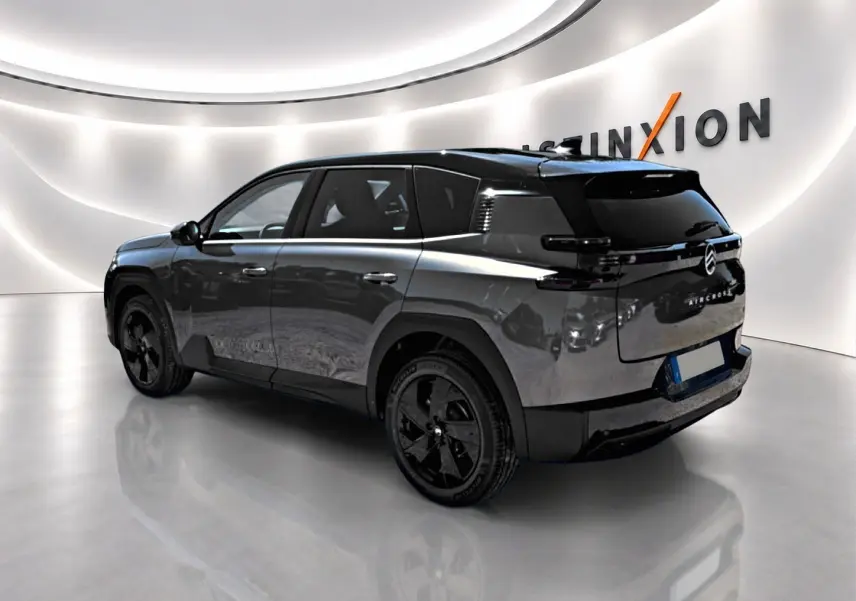 Vue 3/4 arrière droite du Citroën C5 Aircross gris platinium avec toit noir et jantes alliage noires dans un showroom lumineux.