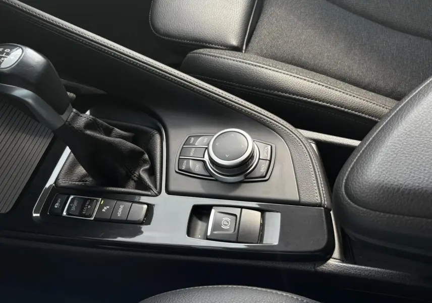 Vue rapprochée de la console centrale noire avec levier de vitesses et commandes du BMW X2 F39 Or Galvanic.