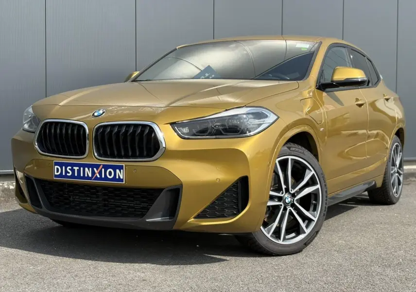 BMW X2 xDrive 25e 2021 en or galvanic, vue 3/4 avant mettant en valeur les jantes alliage bicolores 19 pouces.