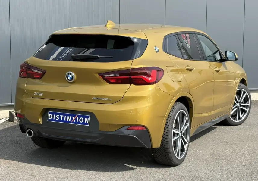 Vue 3/4 arrière droite d'un BMW X2 F39 xDrive 25e or Galvanic avec jantes alliage bicolores et hayon électrique.