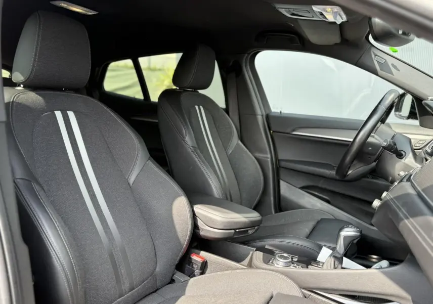 Intérieur de la BMW X2 F39 2021 vu côté droit, sièges sport noirs avec bandes grises et accoudoir central.