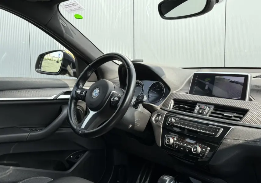 Vue intérieure côté conducteur du BMW X2 2021 avec volant M cuir, écran GPS et tableau de bord noir.