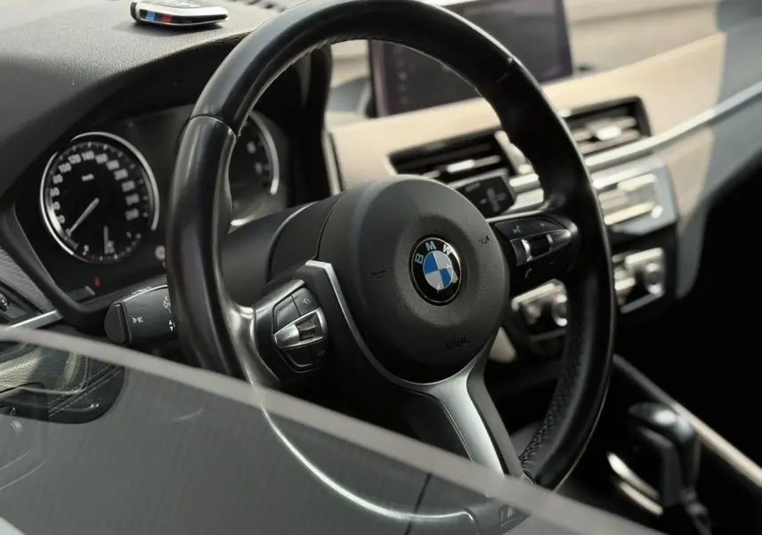 Vue rapprochée du volant cuir M et tableau de bord du BMW X2 F39 avec commandes multifonctions et écran GPS.