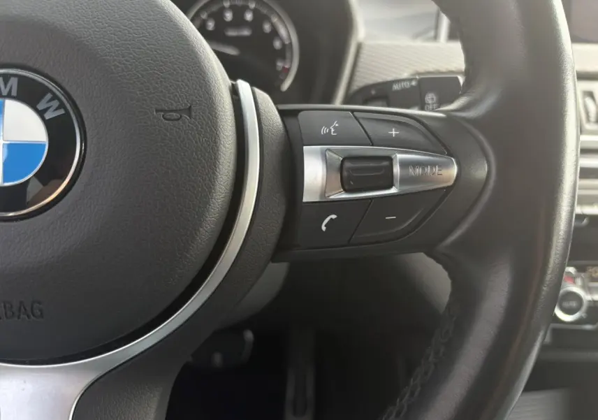 Gros plan sur le volant cuir M de la BMW X2 F39, mettant en valeur les commandes multifonctions côté droit.