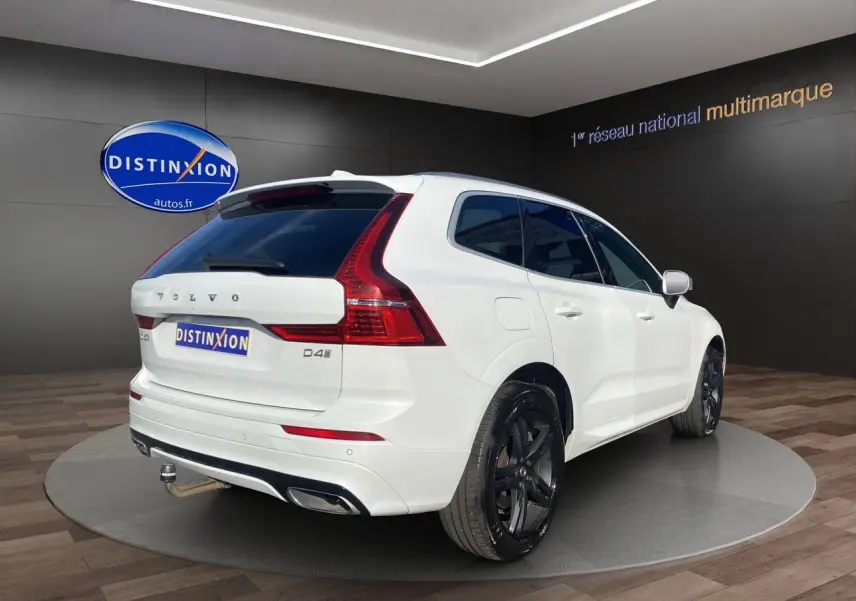 Vue 3/4 arrière droite d'un Volvo XC60 blanc 2019 avec jantes noires et feux arrière LED distinctifs.