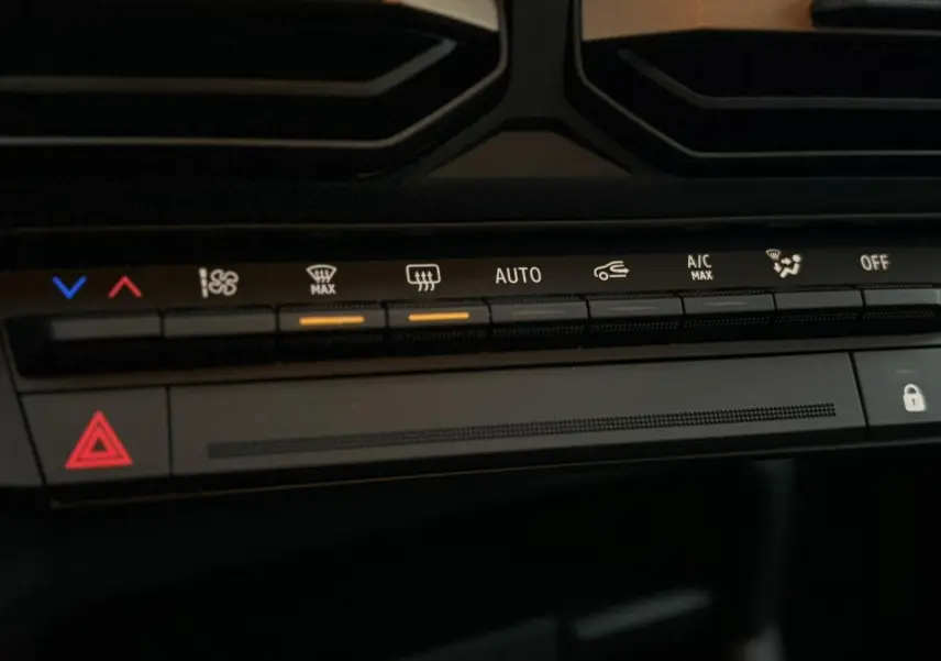 Détail du tableau de bord du Dacia Duster 2026, montrant les commandes de climatisation et d'alerte en lumière ambiante.