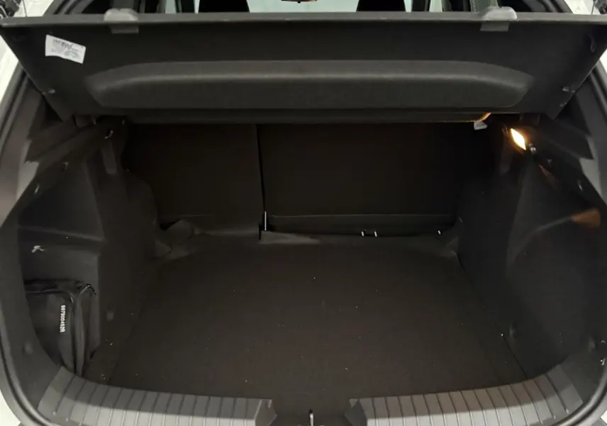 Coffre ouvert du Dacia Duster blanc Glacier, vue intérieure montrant un espace de chargement vide et éclairé.