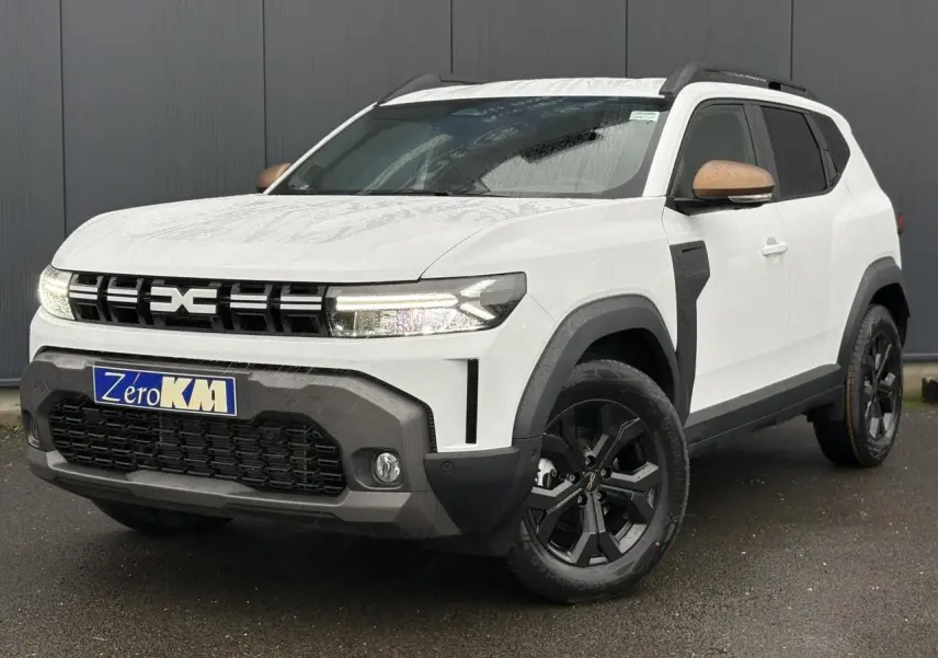 Dacia Duster blanc glacier en 3/4 avant droit, avec coques de rétroviseur brun cuivré et jantes noires.