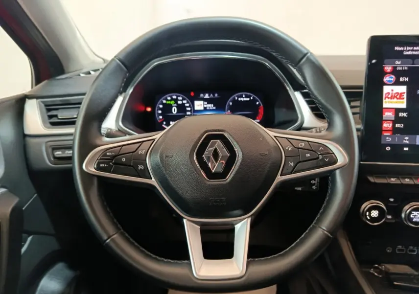 Vue rapprochée du volant noir du Renault Captur 2024 avec tableau de bord numérique et écran tactile central.