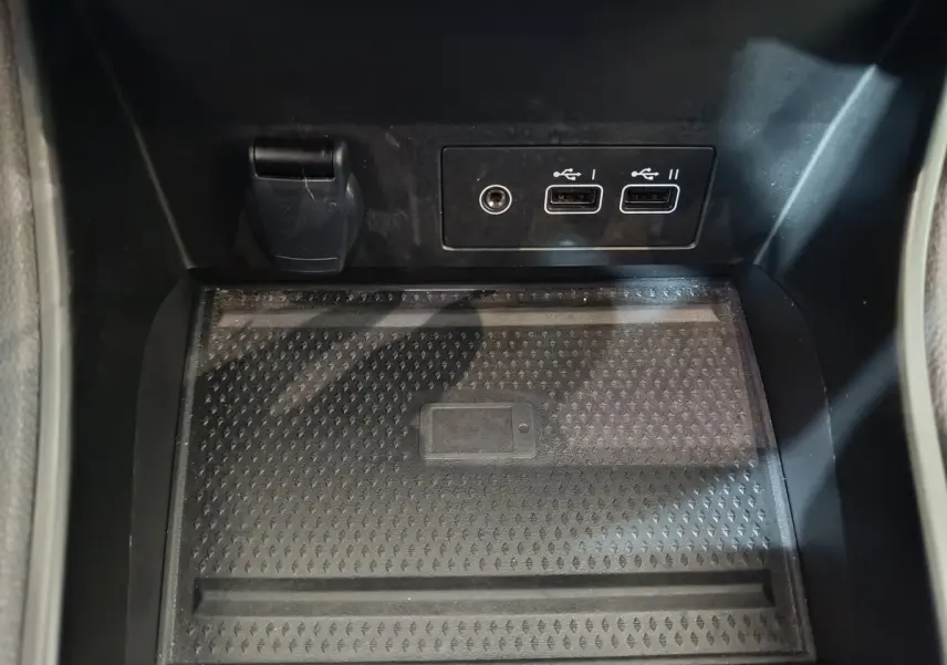 Zone de recharge par induction noire avec ports USB et prise 12V dans le coffre avant du Renault Captur rouge 2024