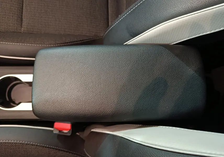 Gros plan sur l'accoudoir central noir entre les sièges avant du Renault Captur Techno TCe 90 rouge 2024.