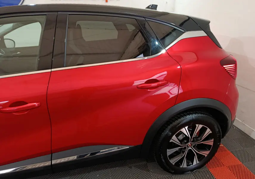 Vue latérale droite du Renault Captur rouge 2024 avec toit noir et jantes alliage distinctives.