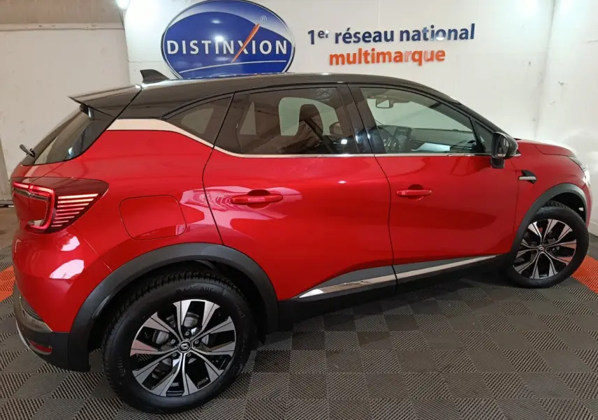Profil côté gauche d'un Renault Captur Techno TCe 90 rouge 2024 en intérieur, avec jantes alliage et toit noir contrasté.