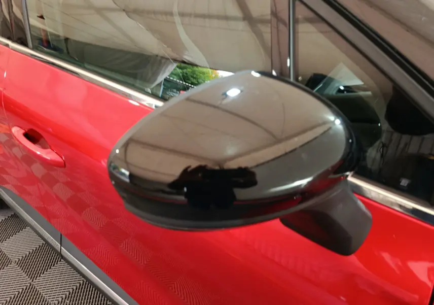Rétroviseur noir brillant côté conducteur du Renault Captur rouge techno TCe 90, vue rapprochée sur la portière avant.