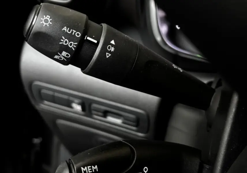Gros plan sur les commandes au volant du Citroën C3 Aircross gris clair, mettant en valeur les réglages des phares et du régulateur de vitesse.