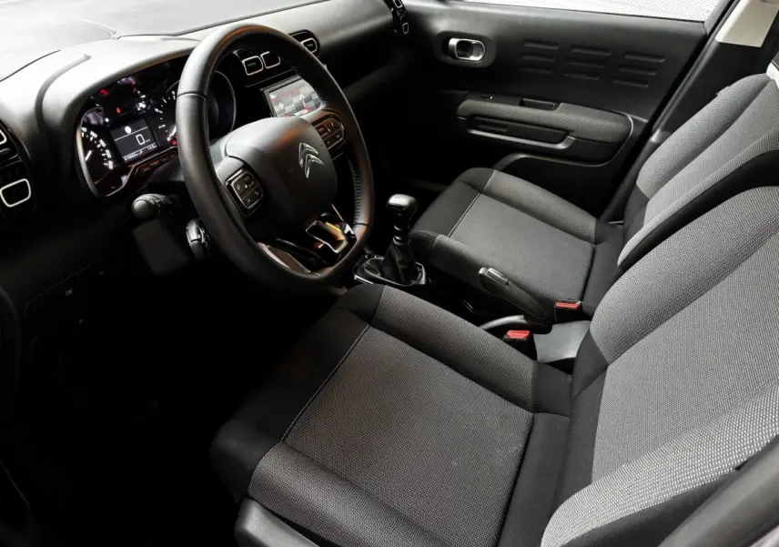 Intérieur avant du Citroën C3 Aircross 2024, vue côté conducteur, sièges gris et tableau de bord avec écran tactile.