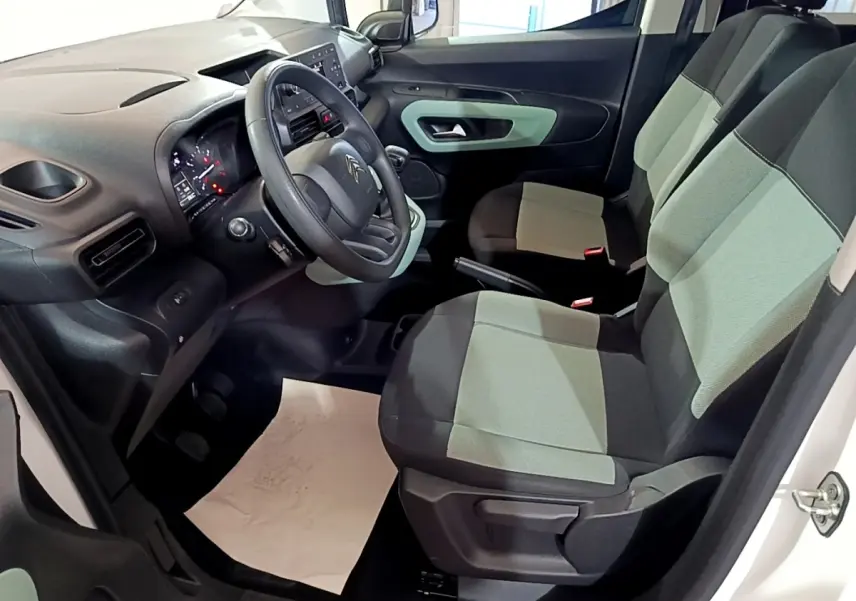 Vue intérieure côté conducteur du Citroën Berlingo blanc 2019, sièges bicolores gris et noir, tableau de bord moderne.