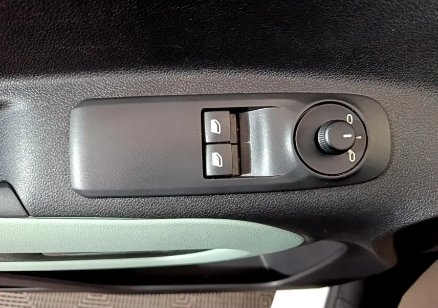 Gros plan sur les commandes de réglage des vitres et des rétroviseurs côté conducteur du Citroën Berlingo blanc, intérieur noir et vert pâle.