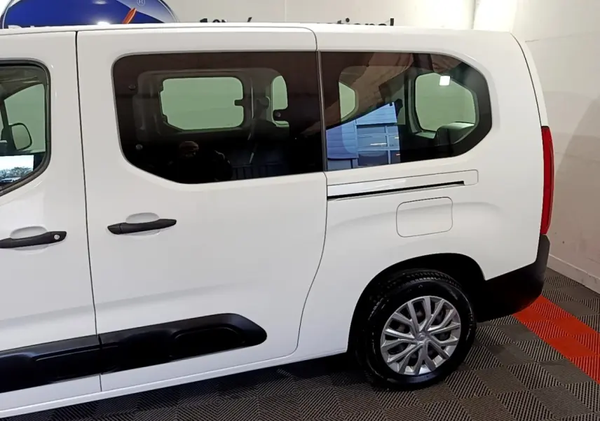 Vue latérale droite d'un Citroën Berlingo XL blanc avec fenêtres teintées et jantes alliage visibles.
