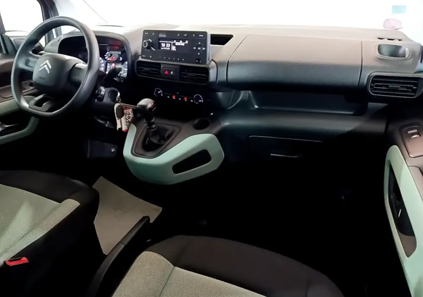 Vue intérieure côté conducteur du Citroën Berlingo XL blanc, montrant le tableau de bord et la console centrale avec boîte manuelle.