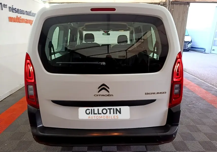 Vue arrière d'un Citroën Berlingo blanc XL, avec feux arrière allumés et logo visible sur un sol à motifs.